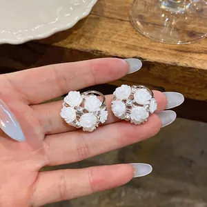 Close-up of elegant white rose stud earrings featuring center crystal accents.