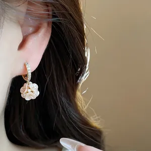 Detailed close-up showing French style flower earrings with zircons and pearls on a model's ear