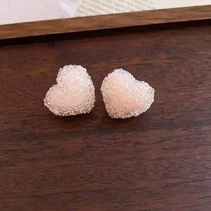 Close-up of elegant peach resin heart stud earrings featuring a sparkling crushed sugar texture.