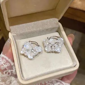 Detailed view of elegant floral pearl earrings with shimmering rhinestones in a gift box