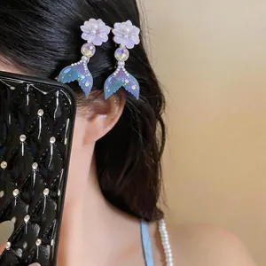 Detailed close-up view of elegant mermaid tail hair clips with pearls worn on dark hair