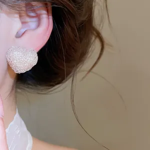 Detailed view of heart-shaped resin stud earring with crushed ice texture worn on ear