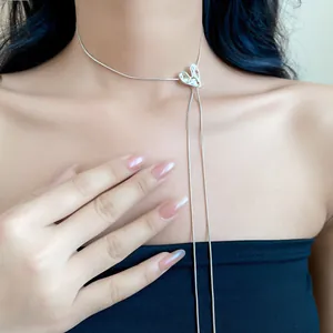 Detailed close-up view of a minimalist silver heart slide necklace on a female model