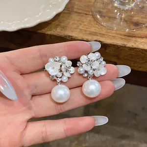 Detailed view of elegant white flower earrings featuring pearls and rhinestones