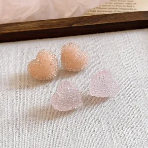 Macro detail of resin heart-shaped earrings with a frosted jelly texture in soft pink.