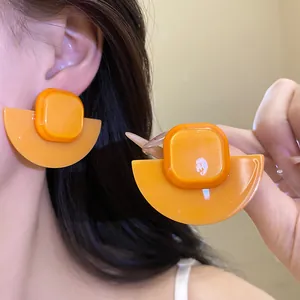Detail view of orange resin geometric earrings with square and fan-shaped design