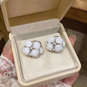 Elegant white rose cluster stud earrings with central sparkling crystal in cream box.