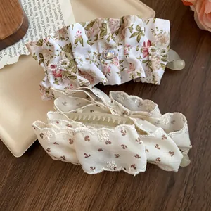 Détail des barrettes banane en tissu floral et dentelle crème avec des détails en zircon