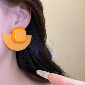 Close-up view of orange resin geometric earrings with square and fan-shaped design