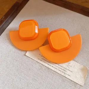 Macro detail of vintage orange resin earrings featuring square and fan-shaped geometric design