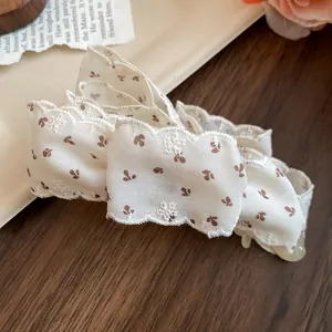 Gros plan d'une pince a cheveux en tissu avec motif floral et bordure en dentelle