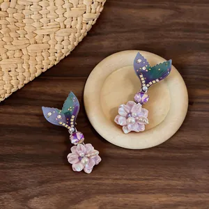 Detailed macro view of mermaid tail hair clips with purple flowers and pearls on wood