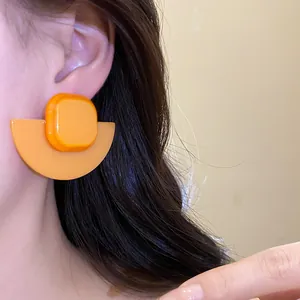 Vintage minimalist resin square fan earrings in bright orange worn on an Asian model ear