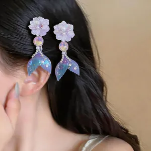 Detail of iridescent mermaid tail hair clips with purple flower and pearl on black hair