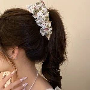 Vue détaillée d'une élégante pince banane en tissu floral avec des nœuds en zircon