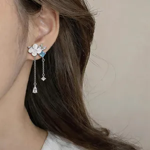 Elegant floral tassel earrings with blue zircon stones worn on model ear detail view