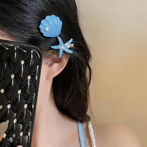 Close-up of blue starfish and shell hair clips worn on side of hair for seaside style.