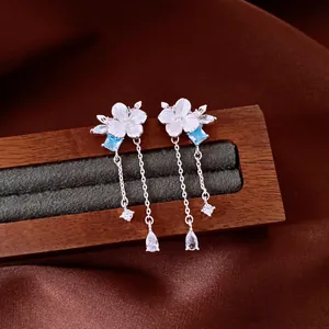 Elegant silver flower tassel earrings with blue zircon detail on wooden jewelry stand