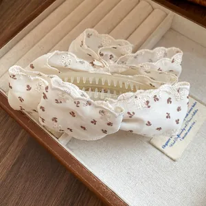 Gros plan de l'élégante pince banane à nœud en tissu fleuri avec bords en dentelle