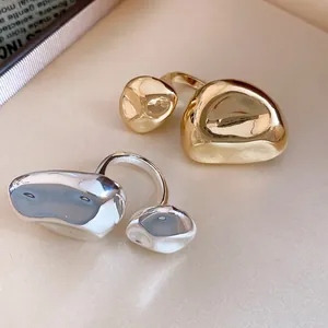 Vista macro dettagliata di anelli aperti a pieghe irregolari in finitura oro e argento