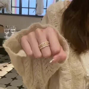 Dettaglio di un anello aperto vintage in pizzo dorato con zirconi su modella in maglia