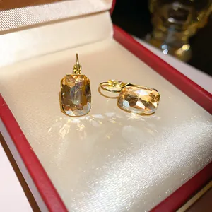 Primo piano di orecchini d'oro con cristallo giallo in scatola rossa da gioielli