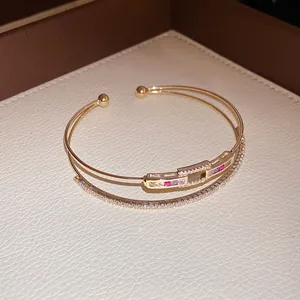 Close-up detail of 18k gold-plated cuff bracelet with white and colorful zircons.