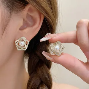 Elegant 14k gold plated flower stud earrings with central pearl and rhinestones.
