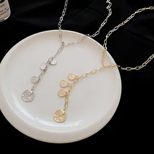 Detailed view of gold and silver coin pendant necklaces on a white plate
