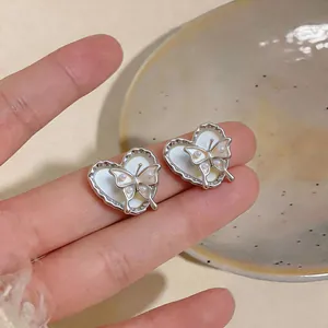 Macro shot of elegant silver heart earrings featuring delicate pearl butterfly details