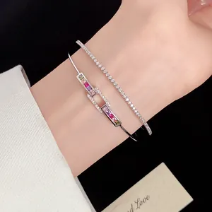 Close-up of silver-toned zircon bangle and tennis bracelet set on a wrist.
