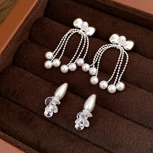 Elegant silver bow earrings with delicate pearl tassels displayed in a brown jewelry box