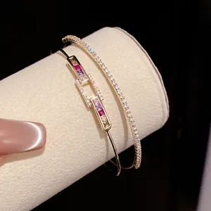 Close-up of 18k gold plated bangles with multi-colored zircon stones on a cream jewelry roll
