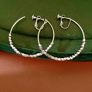 Close-up of faceted metal beads and screw-back mechanism on silver hoop earrings