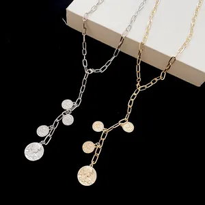 Detailed view of silver and gold plated round portrait coin necklaces on black background