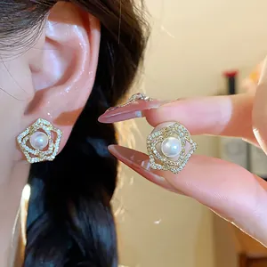 Close-up detail of 14k gold plated flower stud earrings with elegant central pearl