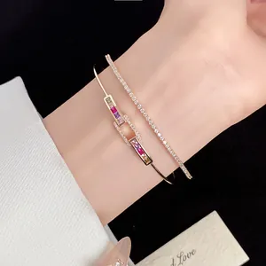 Detail view of 18k gold plated zircon square open bangle and thin tennis bracelet on wrist