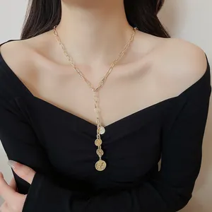 Detailed view of a gold coin portrait pendant necklace on a woman's neckline