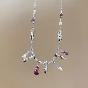 Detailed view of the beaded necklace featuring purple gems, pearls, and silver pendants.