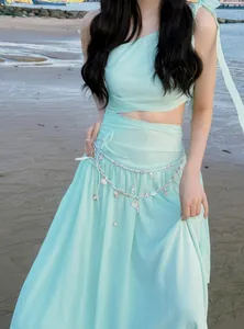 Close-up of elegant pearl and shell tassel waist chain on a mint dress at the beach.