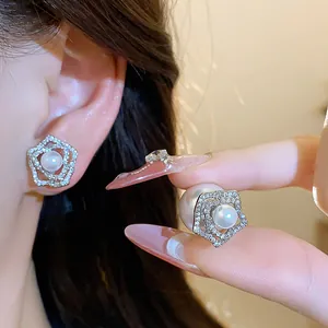 Close-up detail of 14k gold plated flower stud earrings featuring elegant white pearls.