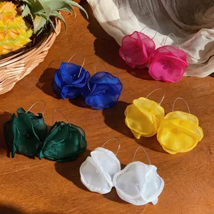 Elegante Chiffon-Blumen-Ohrringe in fünf leuchtenden Farben auf einer rustikalen Holzoberfläche