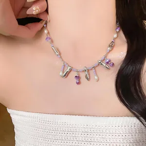 Detailed macro view of minimalist acrylic pearl necklace with purple beads on model's neck