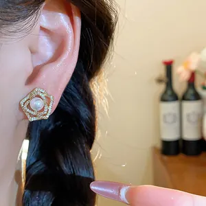 Detailed close-up view of elegant flower-shaped 14k gold-plated pearl earrings on ear.