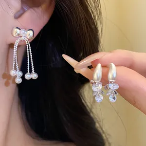 Close-up detail of elegant silver needle bowknot pearl tassel earrings and zircon studs