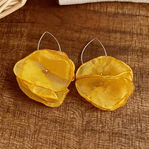 Elegante gelbe Chiffonblumen-Ohrhaken mit zarten Blütenschichten auf einem Holzhintergrund