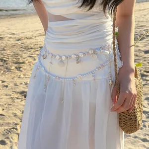 Close-up of beach vacation style body chain featuring pearls, shells and flowers