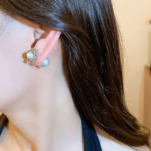 Detailed view of elegant flower pearl stud earrings with 14k gold plating on model
