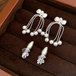 Close-up of elegant bow pearl tassel earrings and teardrop crystal studs in jewelry box
