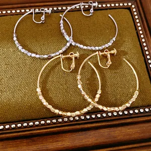 Close-up of 14K gold plated faceted beaded hoop clip-on earrings in gold and silver